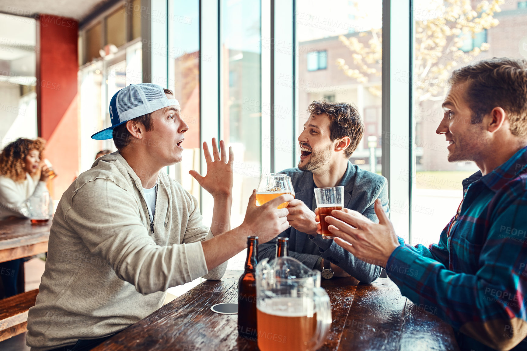 Buy stock photo Shot of three male friends having drinks in a bar