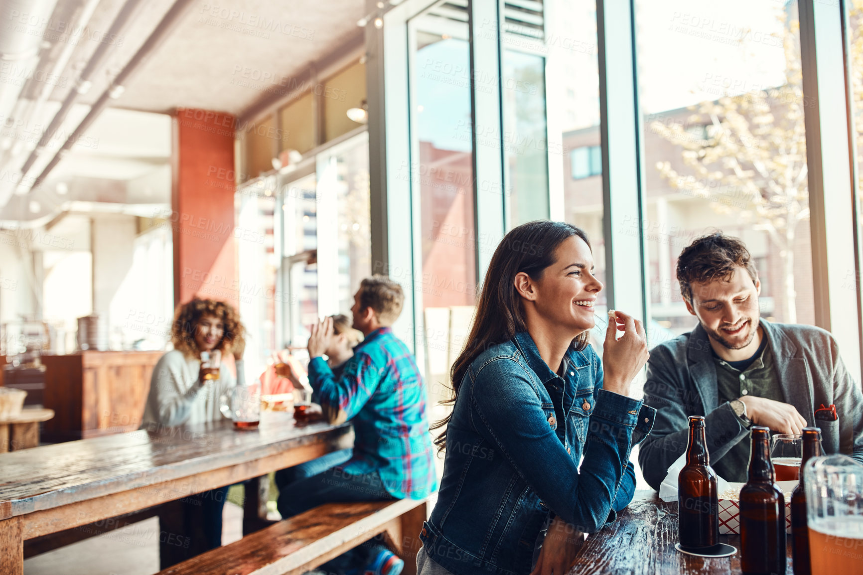 Buy stock photo Cropped shot of a young couple having drinks in a bar with people blurred in the background