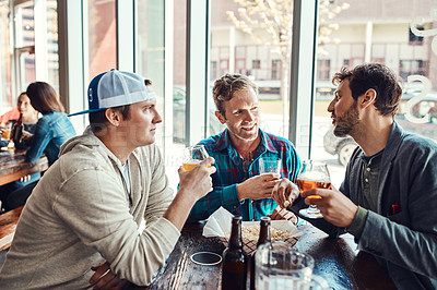 Buy stock photo Shot of three male friends having drinks in a bar