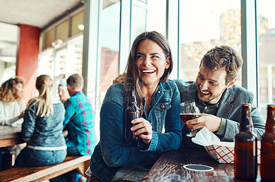 Buy stock photo Cropped shot of a young couple having drinks in a bar with people blurred in the background