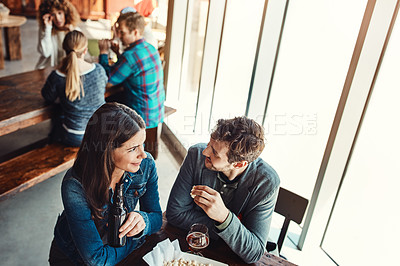 Buy stock photo Cropped shot of a young couple having drinks in a bar with people blurred in the background
