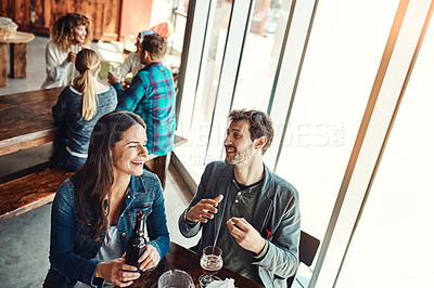 Buy stock photo Cropped shot of a young couple having drinks in a bar with people blurred in the background