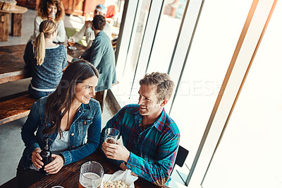 Buy stock photo Cropped shot of a young couple having drinks in a bar with people blurred in the background