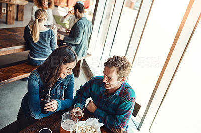 Buy stock photo Cropped shot of a young couple having drinks in a bar with people blurred in the background