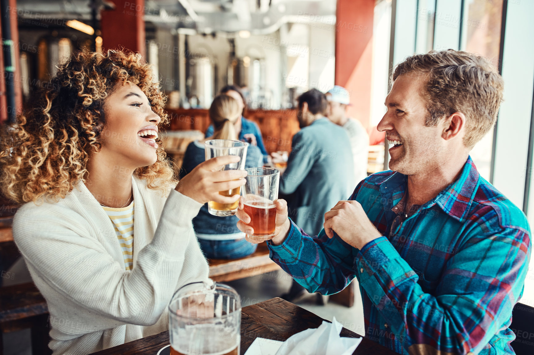 Buy stock photo Cropped shot of a young couple having drinks in a bar with people blurred in the background