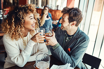 Buy stock photo Cropped shot of a young couple having drinks in a bar with people blurred in the background