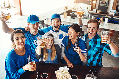 Buy stock photo Shot of a group of friends toasting with beers while watching a sports game at a bar