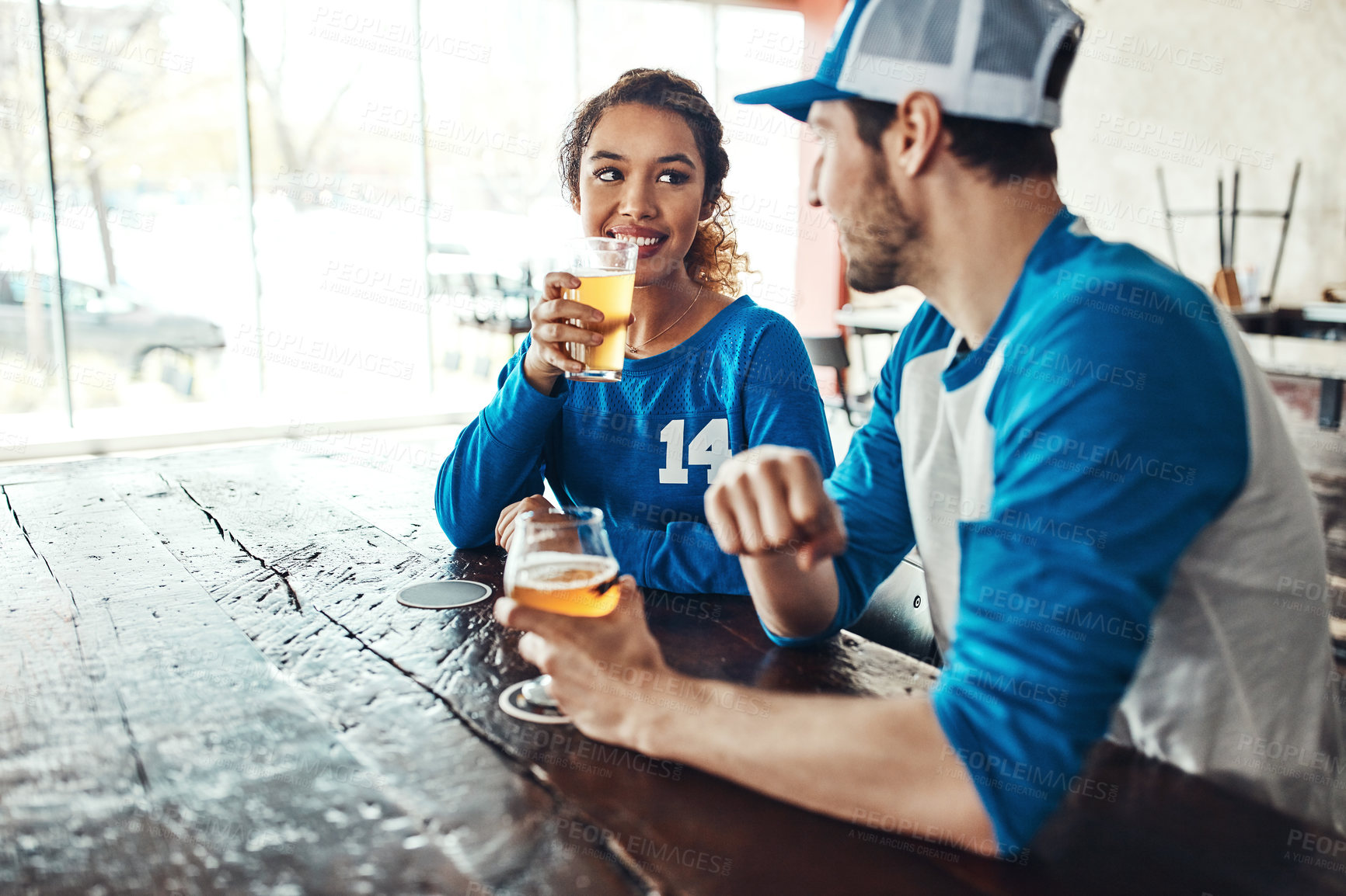 Buy stock photo Sports, speaking or couple in pub with alcohol, love or social celebration of competition together. Relax, soccer game or people in bar for watch party, beer drinks or fans at diner for happy hour