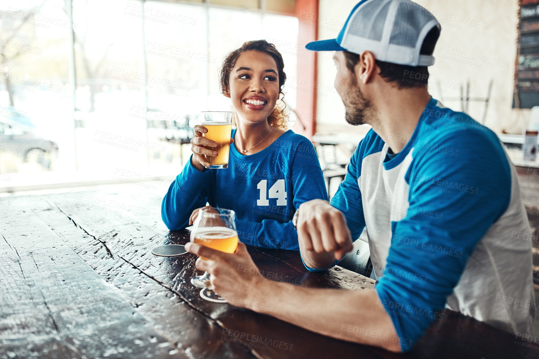 Buy stock photo Sports, speaking or couple in pub with beer, popcorn or social celebration of competition together. Relax, soccer game or people in bar for watch party, alcohol drinks or fans at diner for happy hour