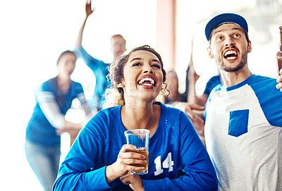 Buy stock photo Shot of a young man and woman having beers while watching a sports game at a bar