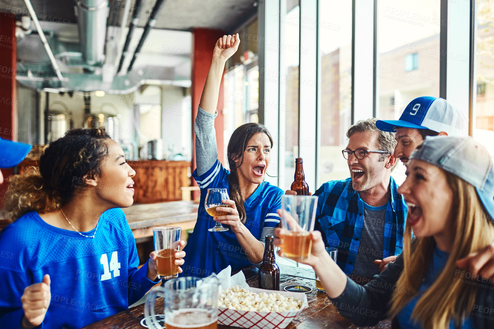 Buy stock photo Shot of a group of friends watching their favorite team live in a sports bar
