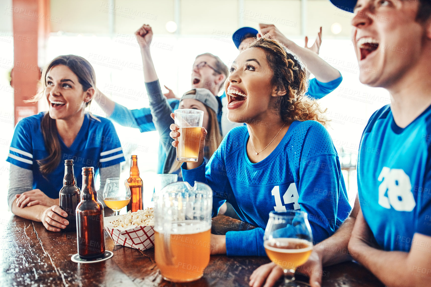 Buy stock photo Shot of a group of friends watching their favorite team live in a sports bar