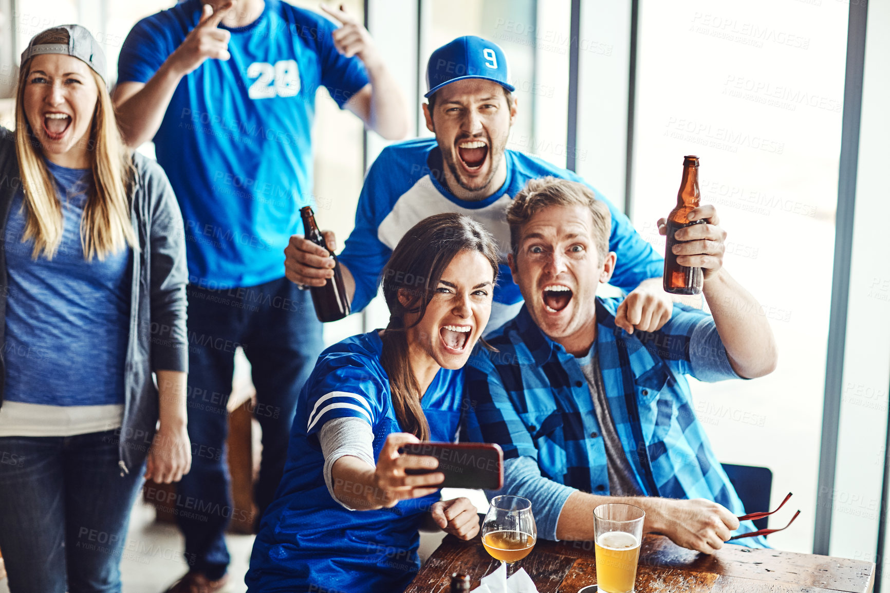 Buy stock photo A group of excited friends cheering on their favourite team at the bar