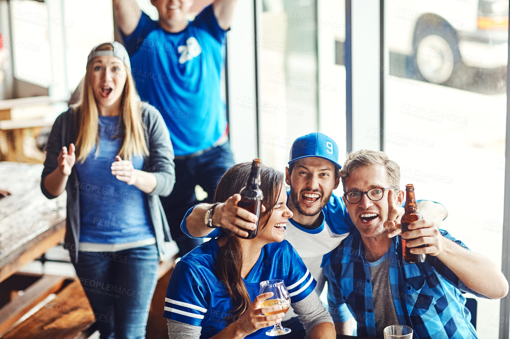 Buy stock photo A group of excited friends cheering on their favourite team at the bar