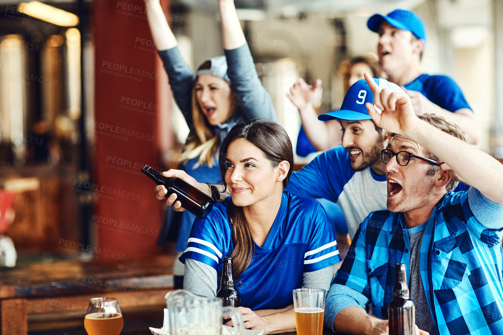 Buy stock photo A group of excited friends cheering on their favourite team at the bar