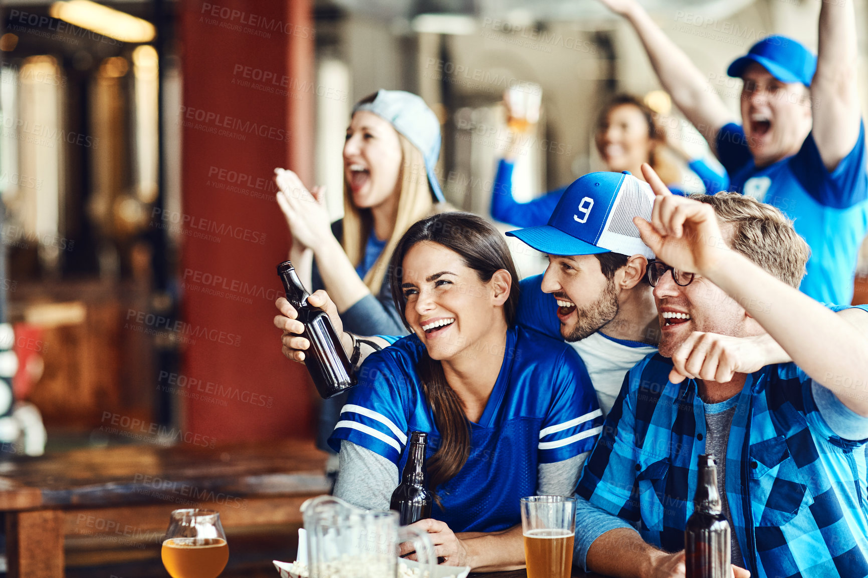 Buy stock photo A group of excited friends cheering on their favourite team at the bar