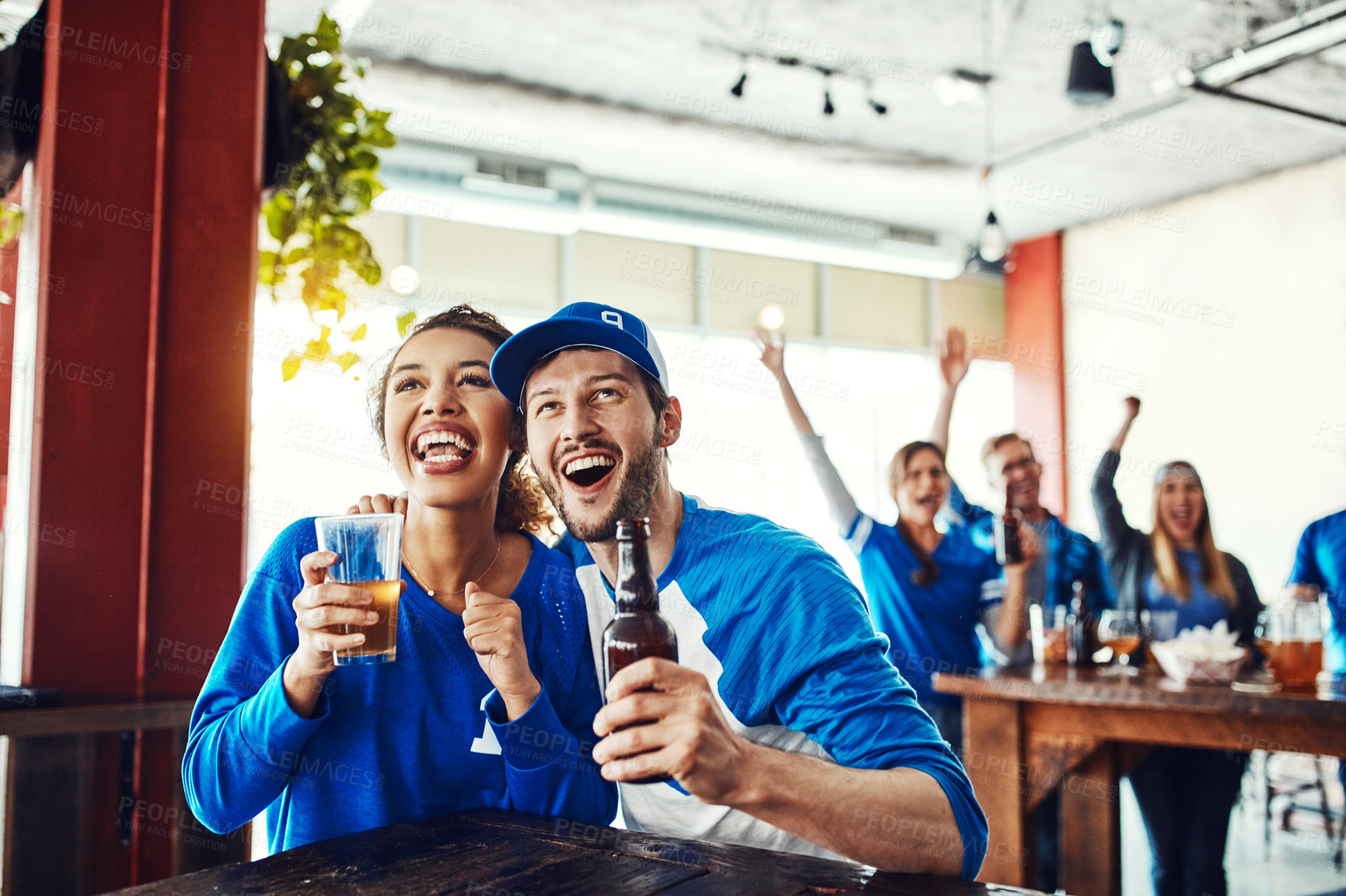 Buy stock photo Shot of a young couple having beer while watching the game in a bar