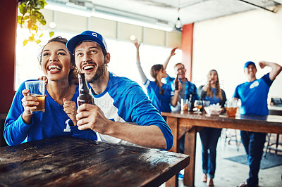 Buy stock photo Shot of a young couple having beer while watching the game in a bar