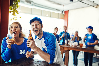 Buy stock photo Shot of a young couple having beer while watching the game in a bar