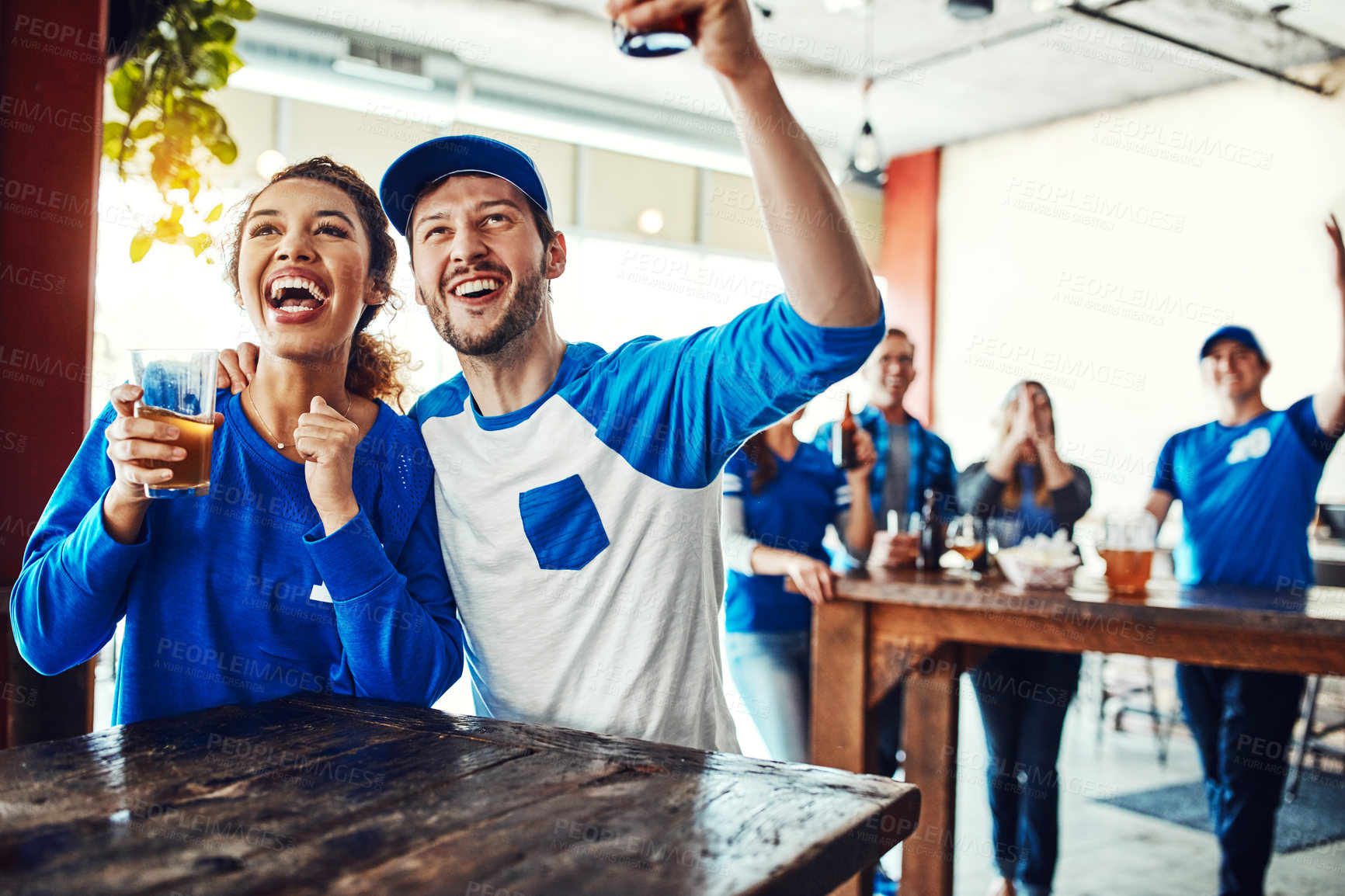 Buy stock photo Shot of a young couple having beer while watching the game in a bar