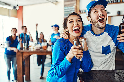 Buy stock photo Shot of a young couple having beer while watching the game in a bar