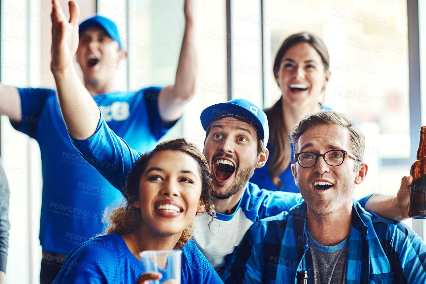 Buy stock photo A group of excited friends cheering on their favourite team at the bar