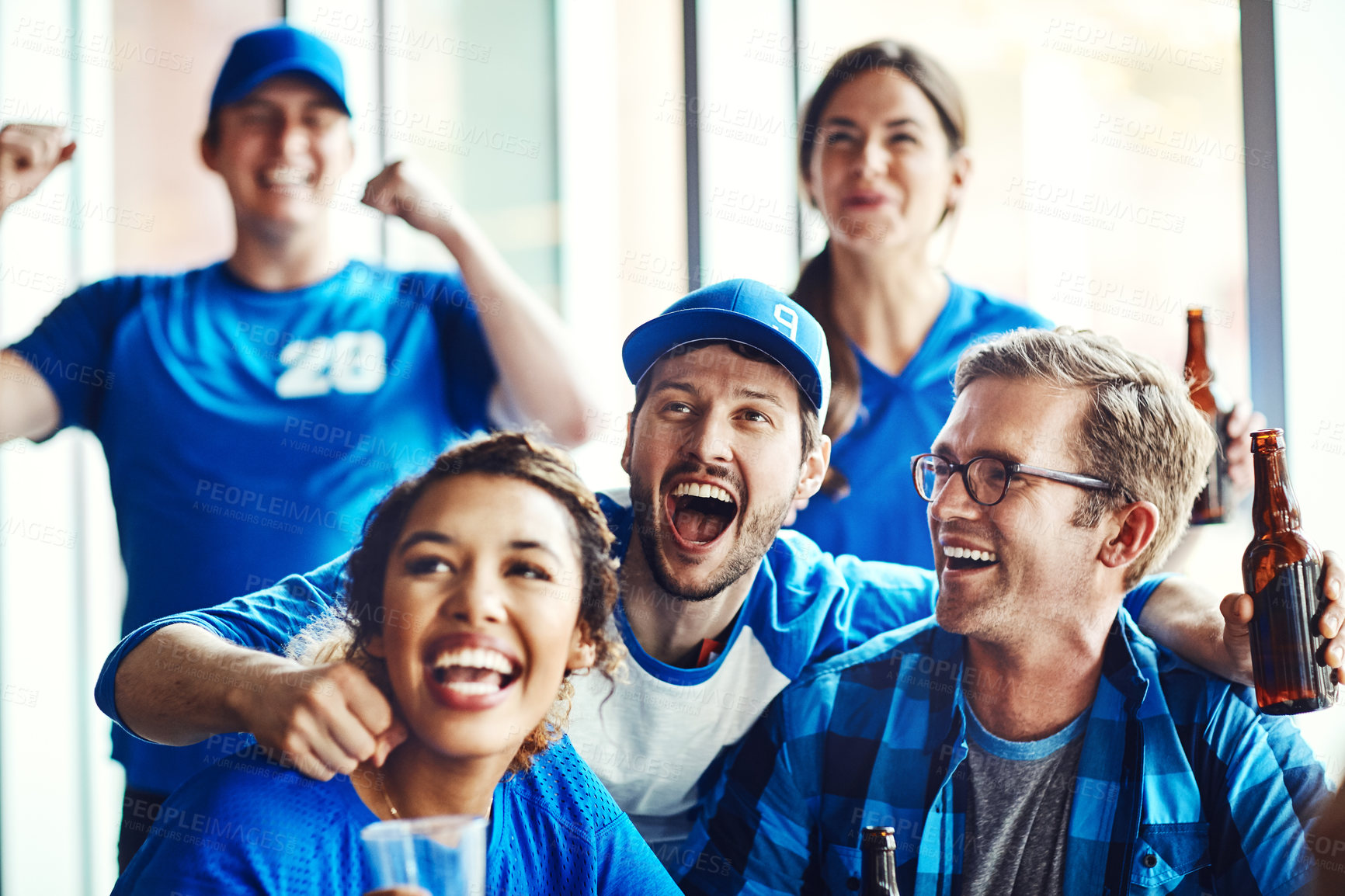 Buy stock photo A group of excited friends cheering on their favourite team at the bar