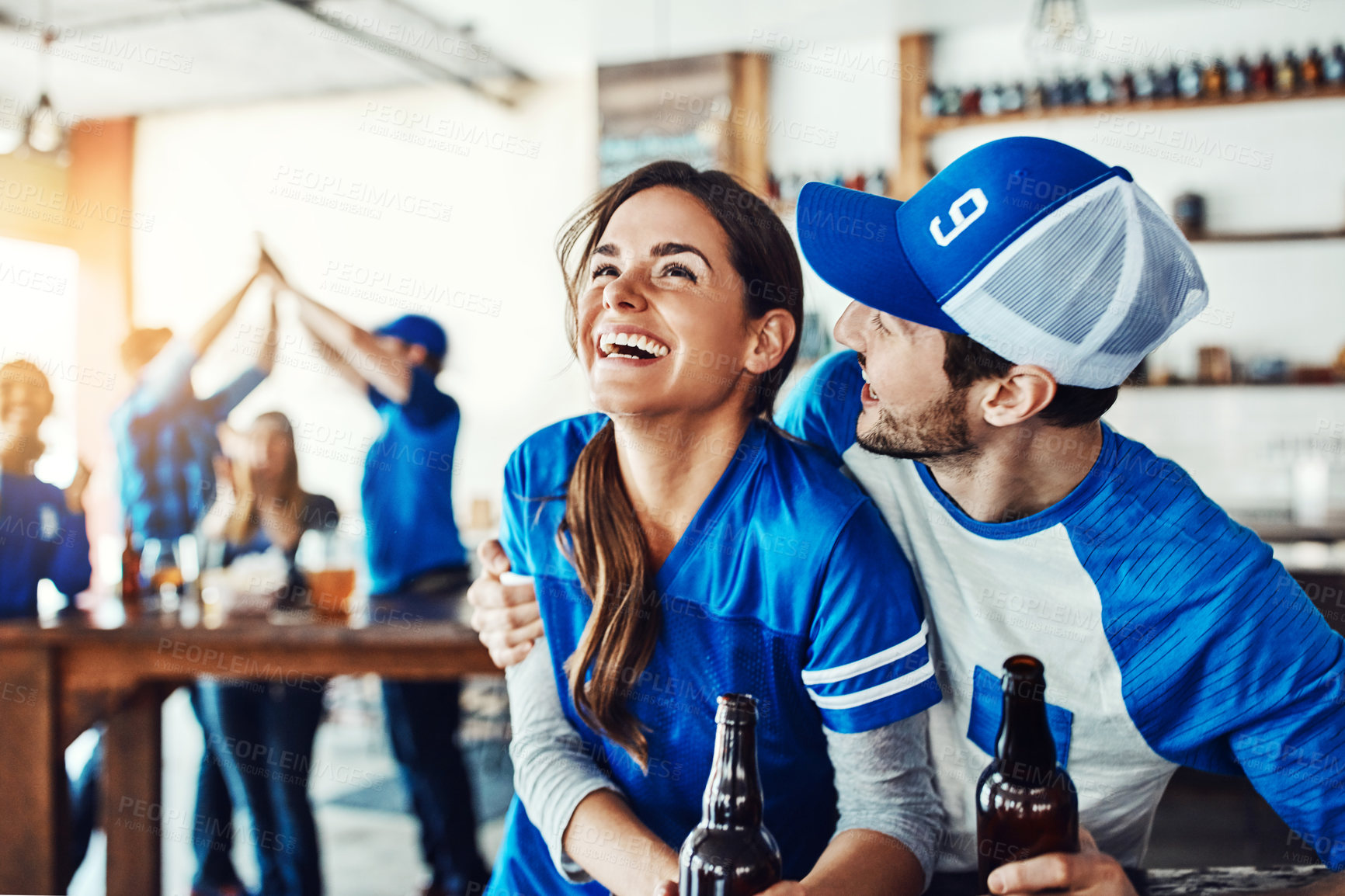 Buy stock photo Shot of a young couple having beer while watching the game in a bar