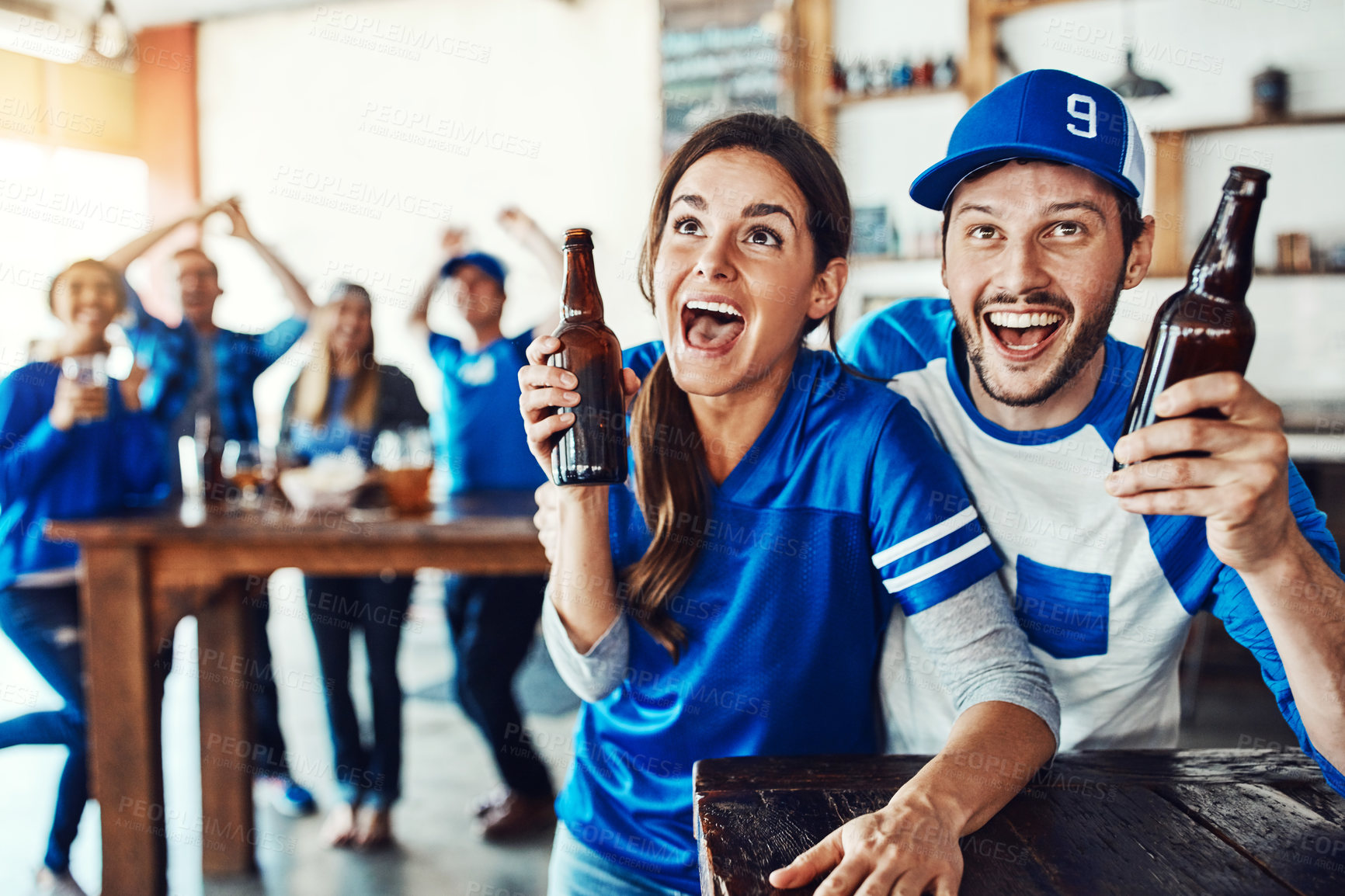 Buy stock photo Shot of a young couple having beer while watching the game in a bar