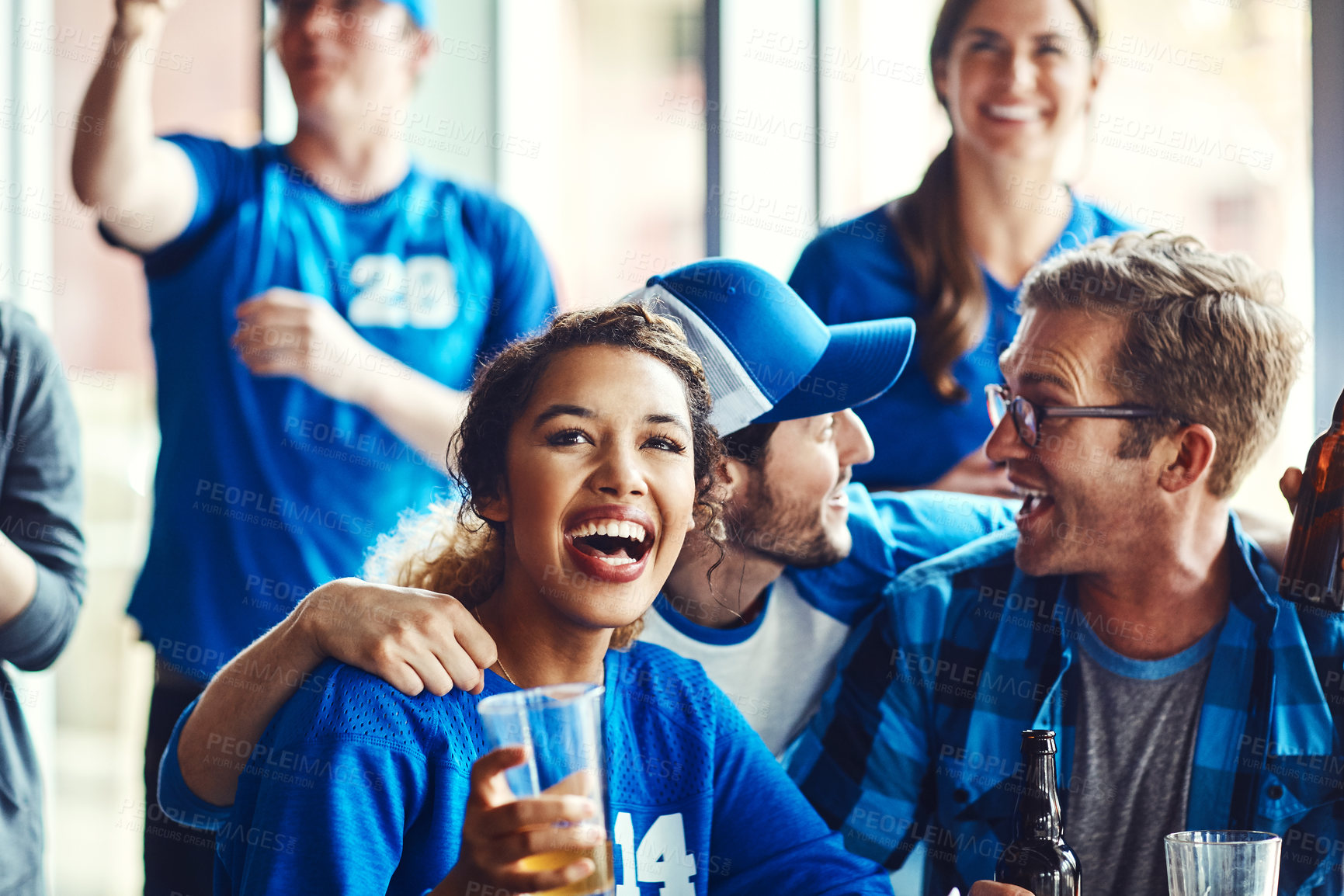 Buy stock photo A group of excited friends cheering on their favourite team at the bar