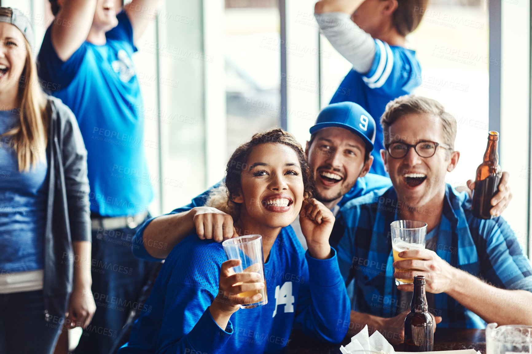 Buy stock photo A group of excited friends cheering on their favourite team at the bar