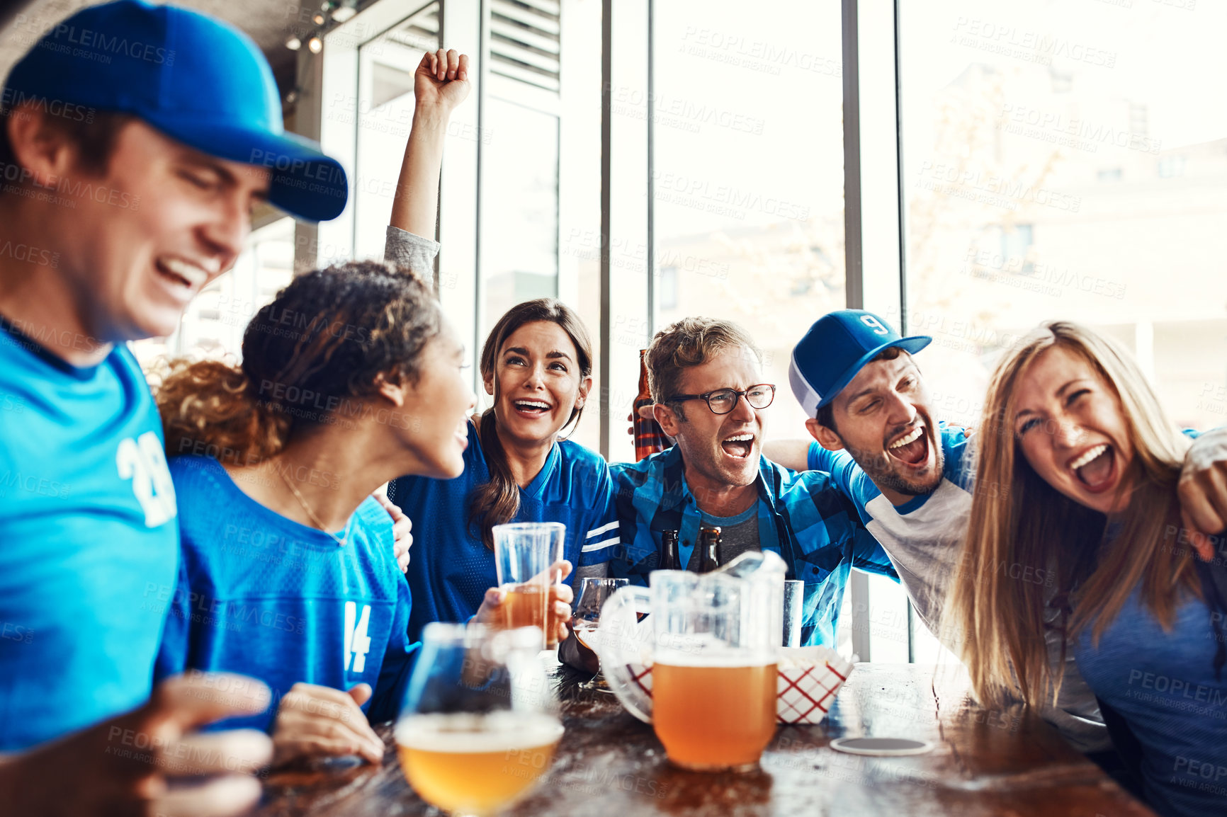 Buy stock photo Shot of a group of friends having beers while watching a sports game at a bar