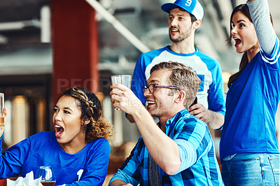 Buy stock photo Shot of a group of friends cheering while watching a sports game at a bar