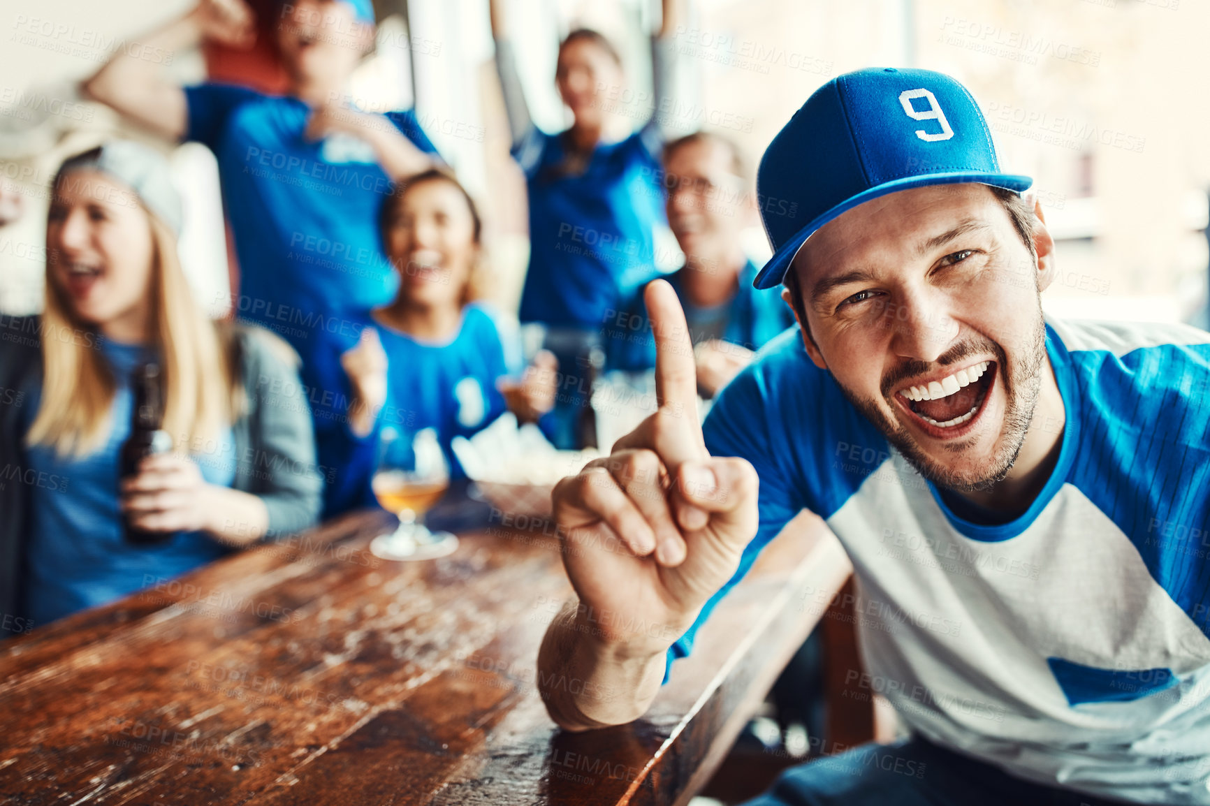 Buy stock photo Portrait of a man holding up one finger while watching a sports game with friends at a bar