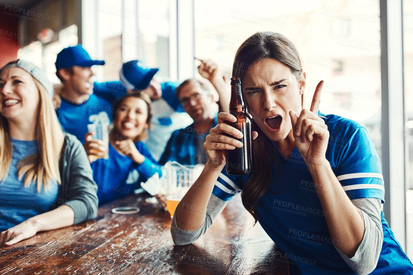 Buy stock photo Portrait of a woman holding up one finger while watching a sports game with friends at a bar