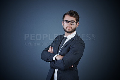 Buy stock photo Studio portrait of a handsome young businessman standing with his arms crossed against a dark background