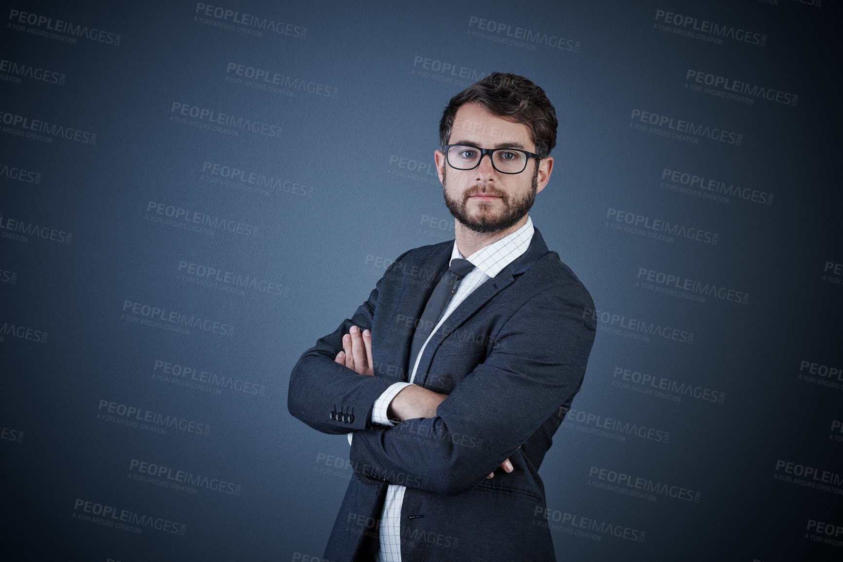 Buy stock photo Studio portrait of a handsome young businessman standing with his arms crossed against a dark background