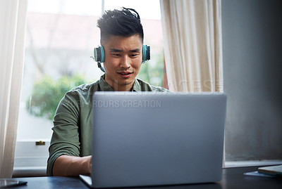 Buy stock photo Cropped shot of a handsome young man listening to music while working from home