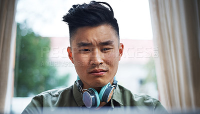 Buy stock photo Cropped shot of a handsome young man working on his laptop at home