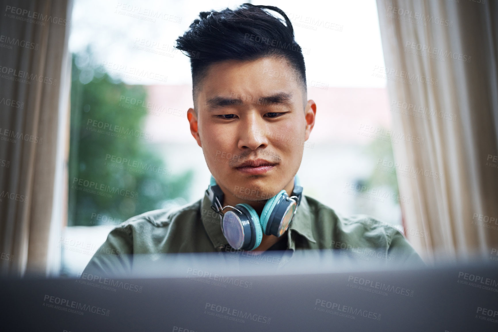 Buy stock photo Cropped shot of a handsome young man working on his laptop at home