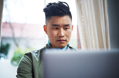 Buy stock photo Cropped shot of a handsome young man working on his laptop at home