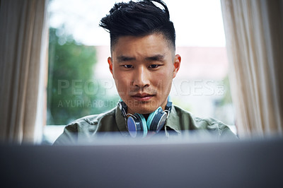 Buy stock photo Cropped shot of a handsome young man working on his laptop at home