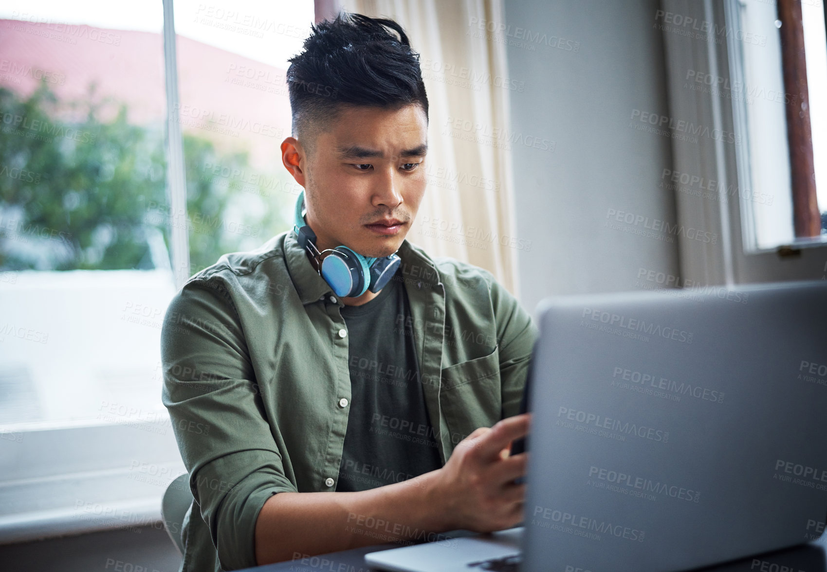 Buy stock photo Cropped shot of a handsome young man working on his laptop at home