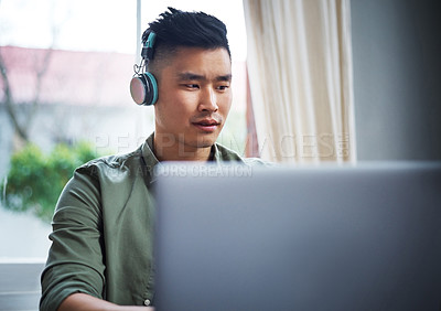 Buy stock photo Cropped shot of a handsome young man listening to music while working from home