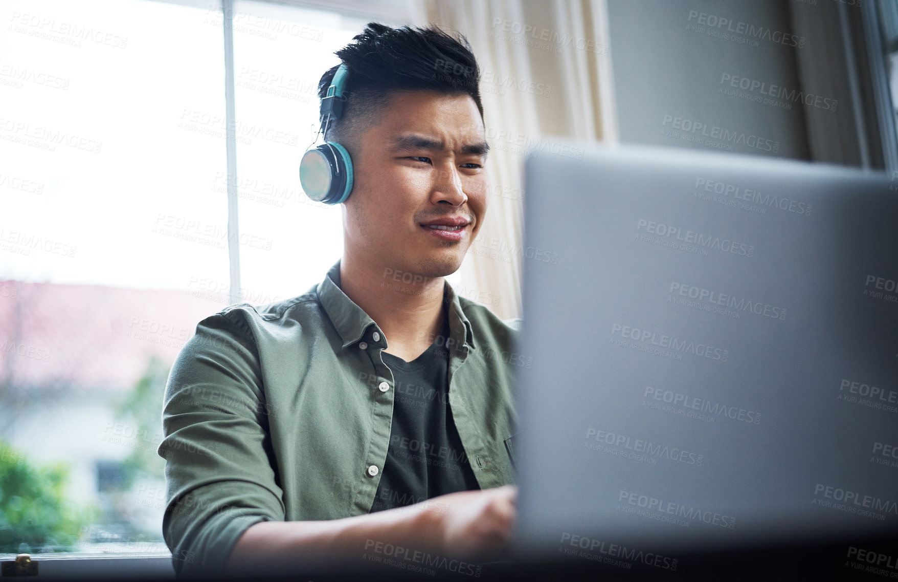 Buy stock photo Cropped shot of a handsome young man listening to music while working from home