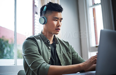 Buy stock photo Cropped shot of a handsome young man listening to music while working from home