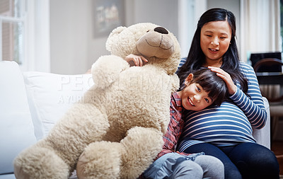 Buy stock photo Cropped portrait of a little girl sitting with her mother and her teddybear on the sofa
