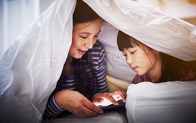 Buy stock photo Cropped shot of an attractive young woman and her daughter using a digital tablet while lying under the covers