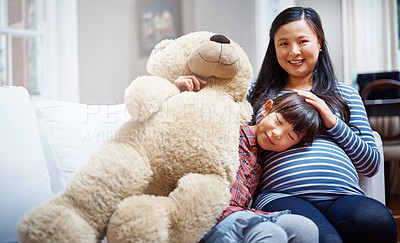 Buy stock photo Cropped portrait of a little girl sitting with her mother and her teddybear on the sofa