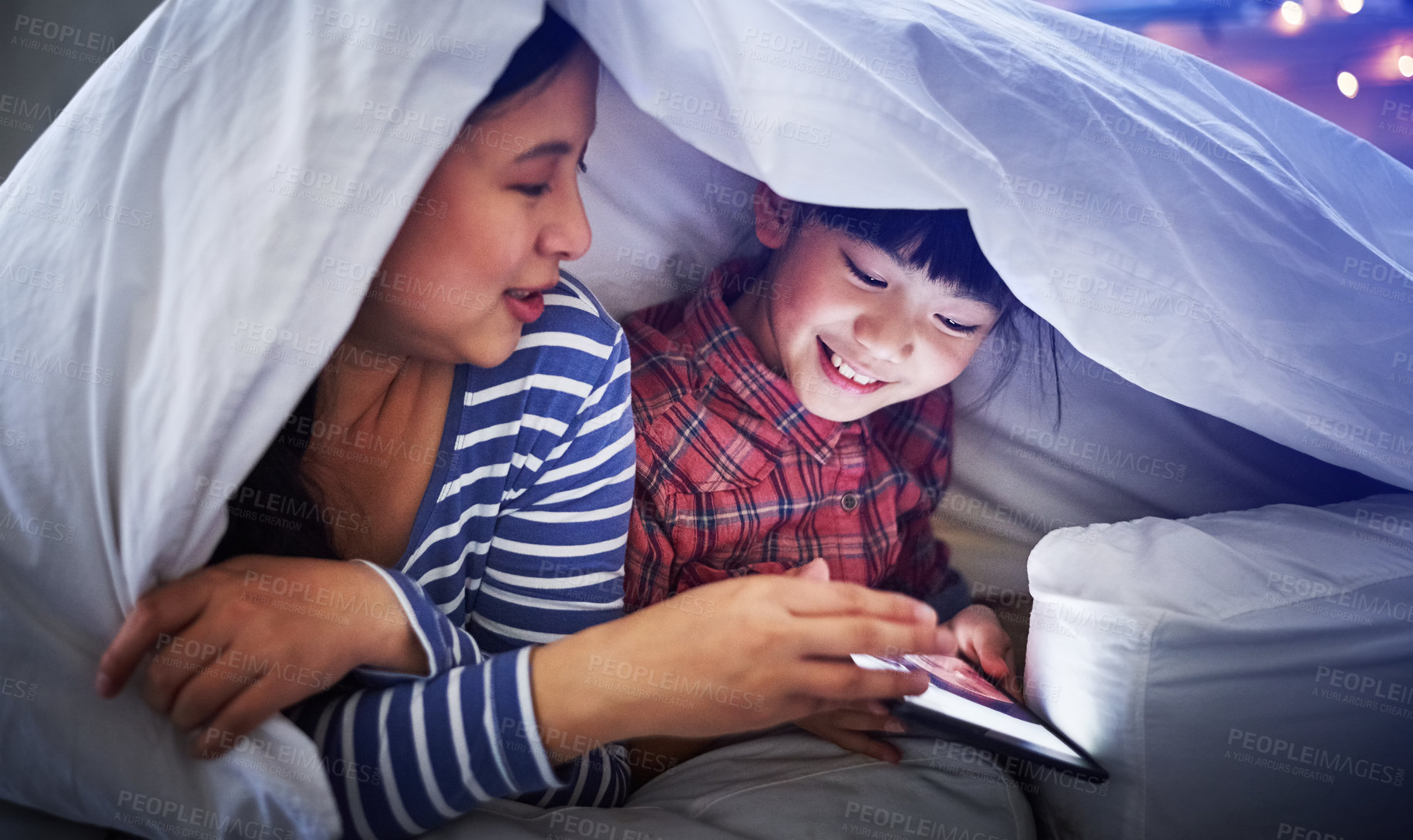 Buy stock photo Cropped shot of an attractive young woman and her daughter using a digital tablet while lying under the covers